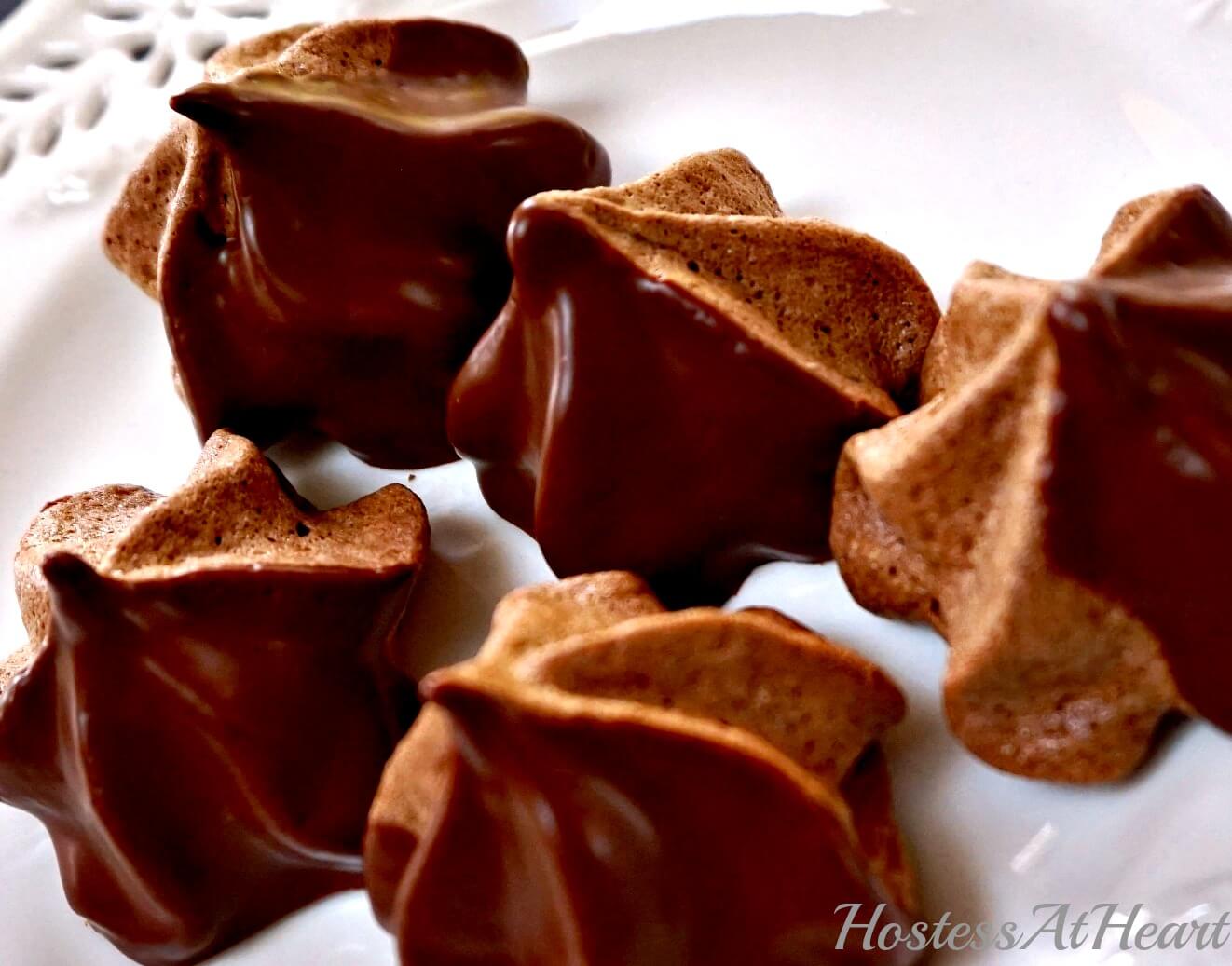 Chocolate Meringue Stars dipped in chocolate ganache sitting on a white plate