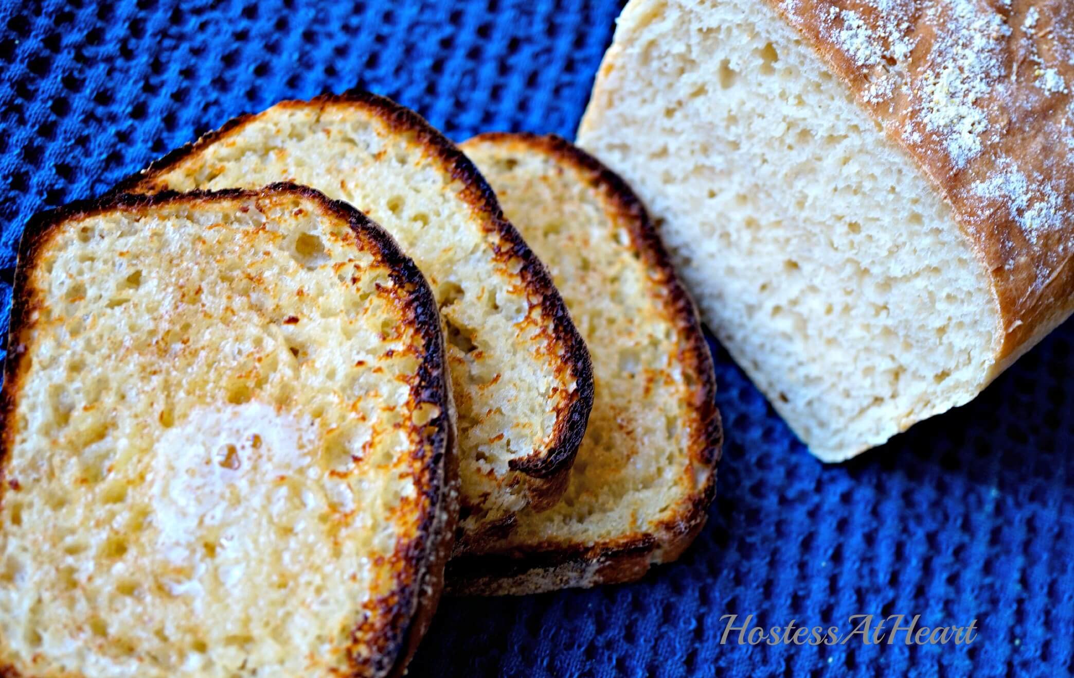 Slices of toasted English Muffin Bread sitting next to the cut loaf.