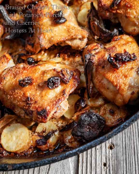 Cast Iron pan filled with cooked chicken thighs with potatoes, Porcini & dried cherries.