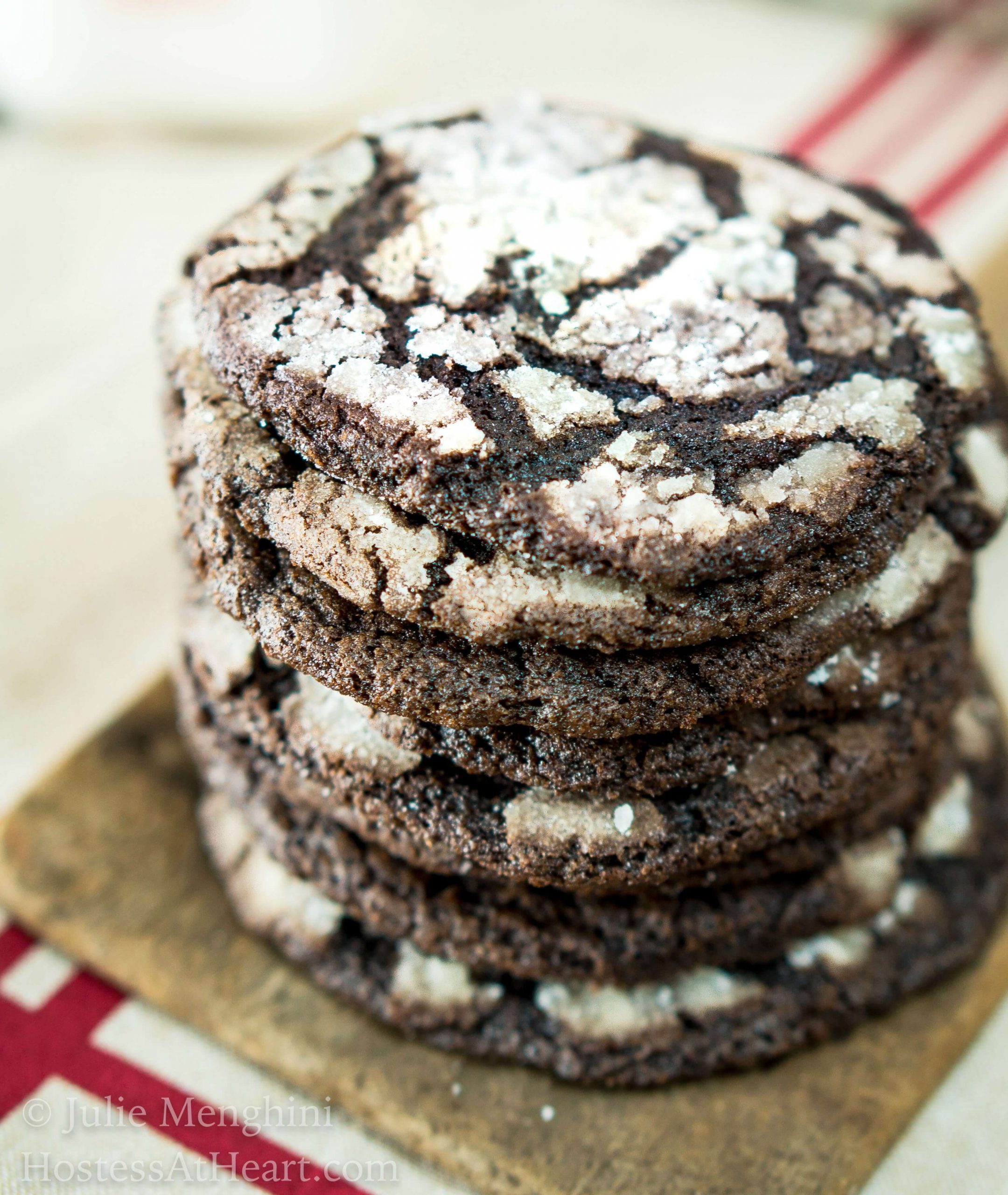 A stack of Dark Chocolate Cookies sitting on a paddle over a red striped napkin.