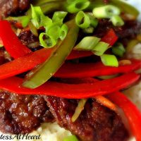 A closeup of Mongolian Beef Stir Fry garnished with red and green peppers.