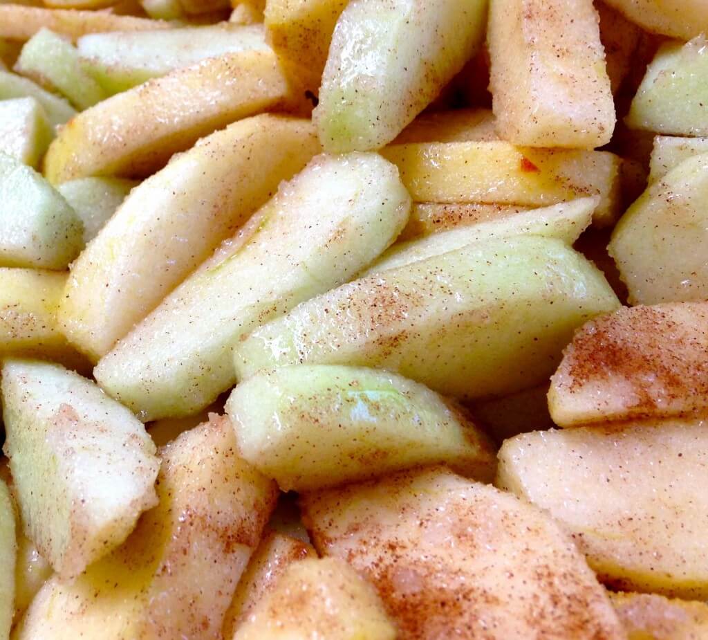 Sliced green apples mixed with cinnamon and sugar.