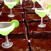 Sliced chocolate brownies frosted in chocolate frosting. Plastic margarita glasses decorate the brownies.