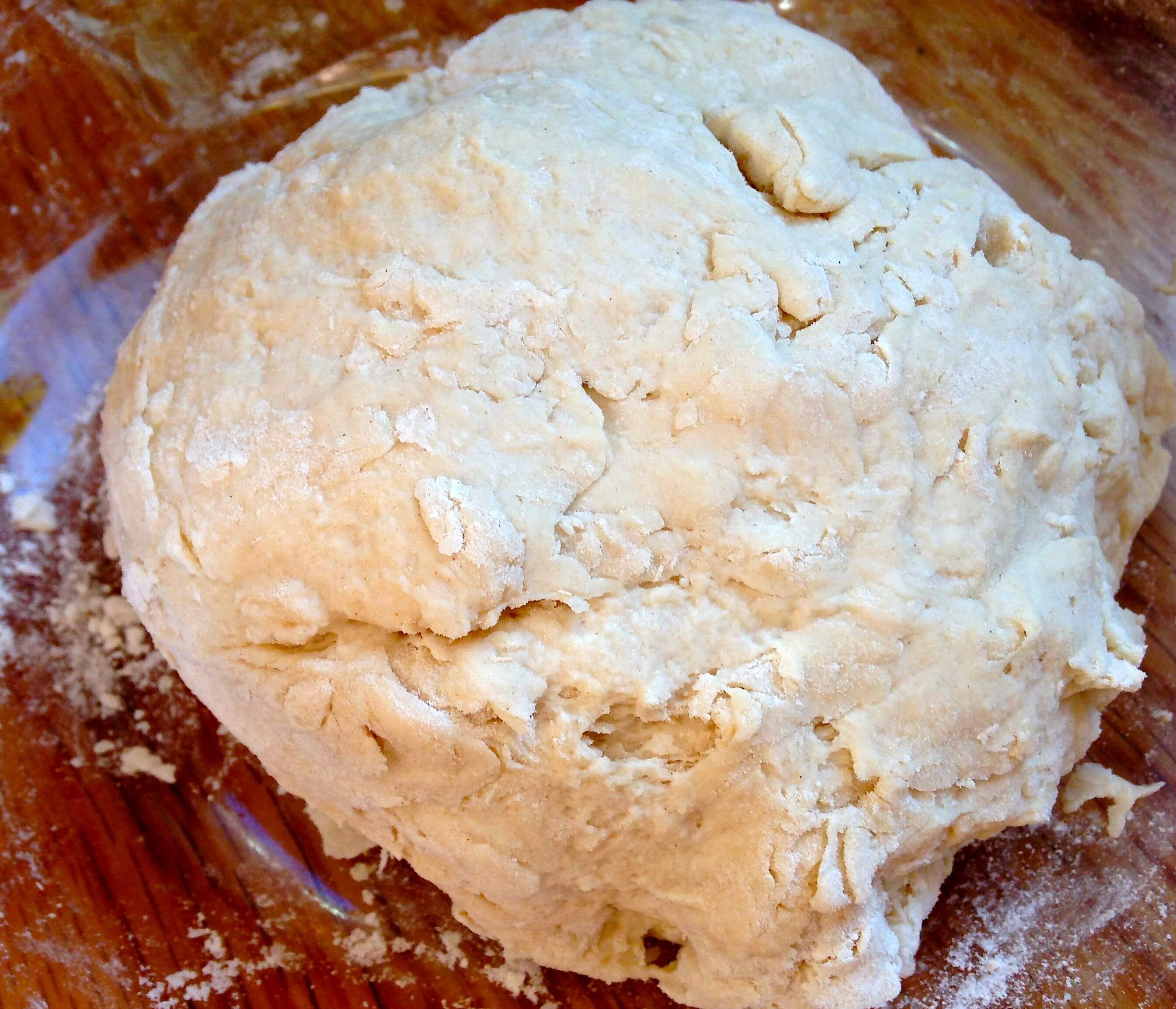 A ball of raw bread dough sitting in a glass bowl.
