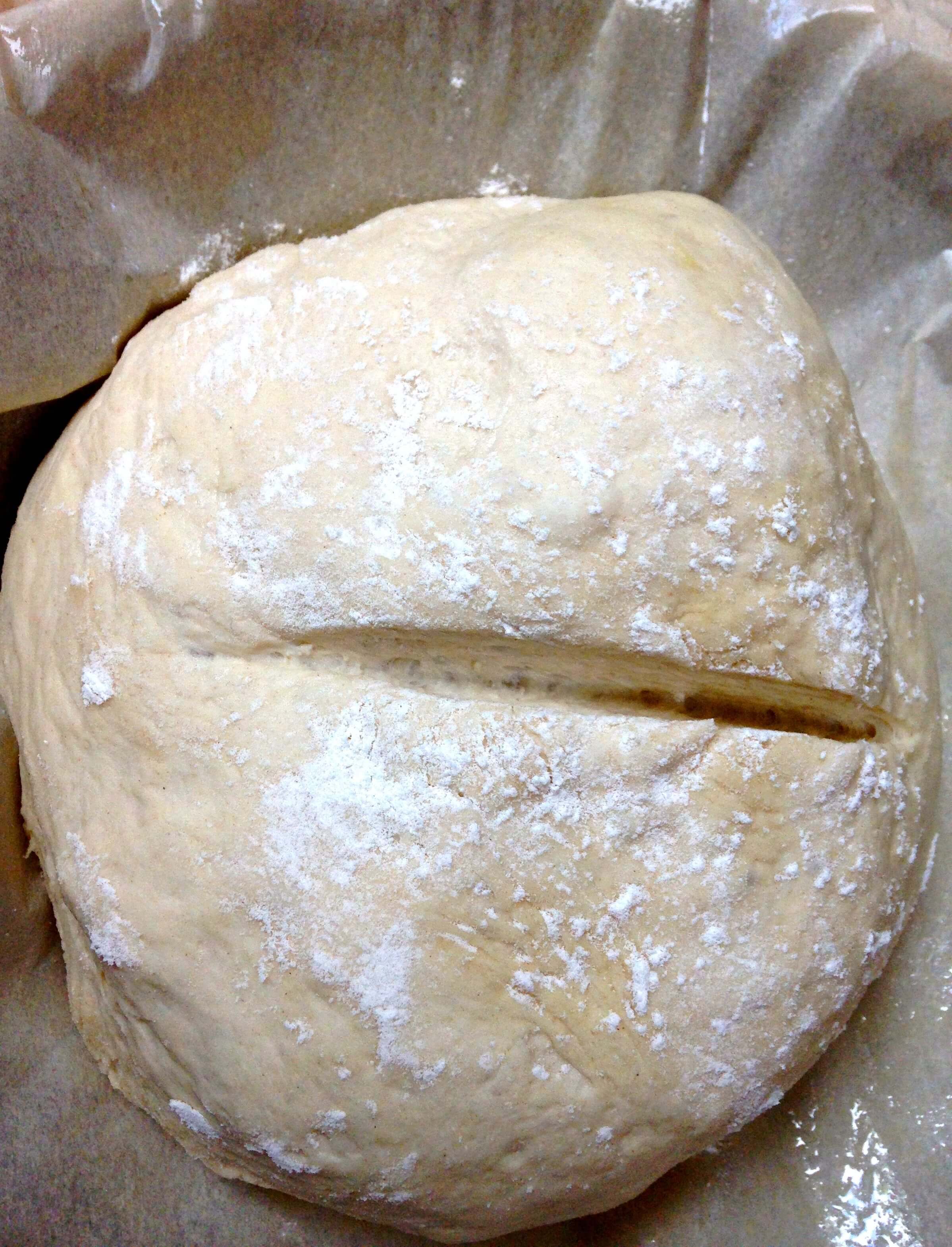 A ball of raw bread dough that\'s been scored.