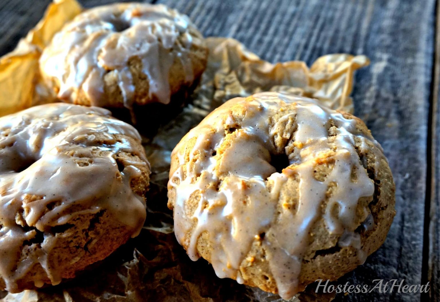 A close up of baked Vanilla Bean Glaze sitting on parchment paper of a wooden background.