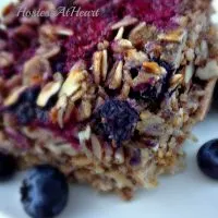A slice of Berry Nut Baked oatmeal with fresh blueberries scattered around it.