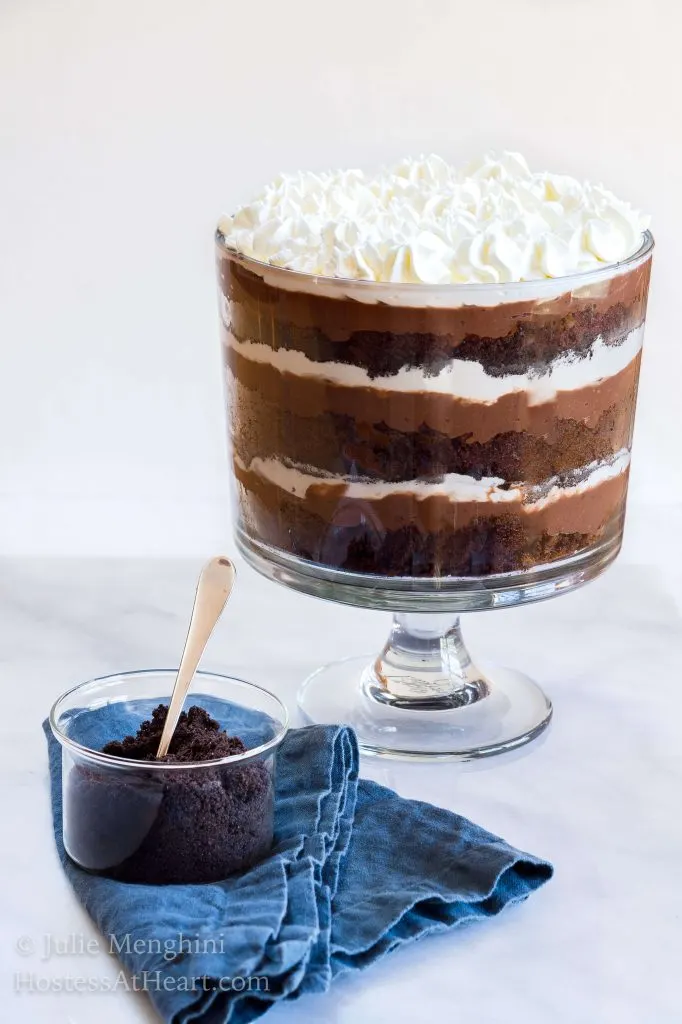 Side view of a trifle bowl layered with chocolate cake, oreo crumbs, whipped cream, and chocolate pudding topped with whipped cream and cookie crumbs.