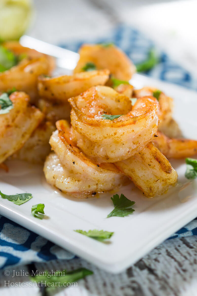 A close up of a white plate of shrimp garnished with cilantro.