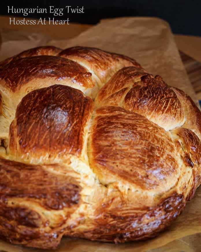 A close up of a loaf of Hungarian Egg Twist Bread sitting on a piece of parchment paper.