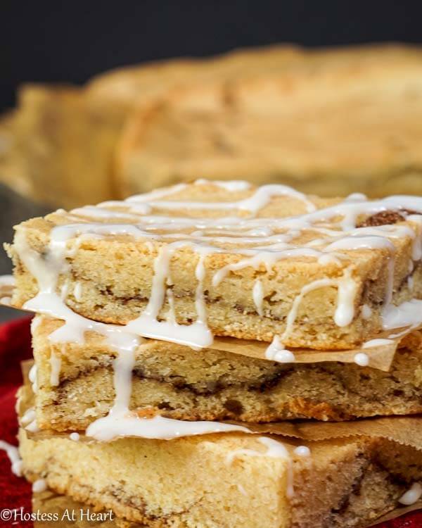 A stack of Snickerdoodle Bars with glaze running down the sides over a red napkin. 