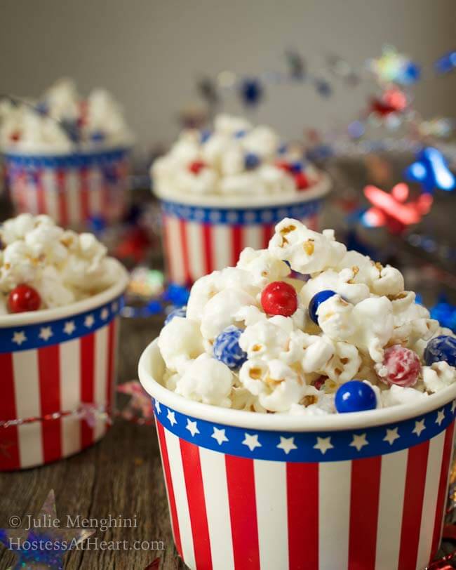 Side view of candied popcorn with pieces of red and blue chocolate candies in a 4 patriotic bowls.