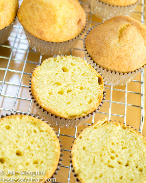 Baked cupcakes with the cup cut from them sitting on a cutting rack.