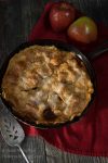 top view of whole apple rhubarb pie with two raw apples