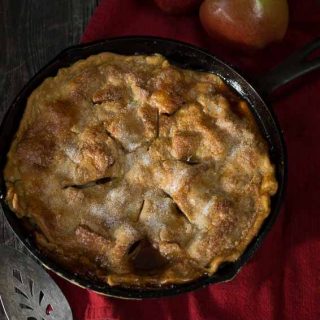 top view of whole apple rhubarb pie with two raw apples