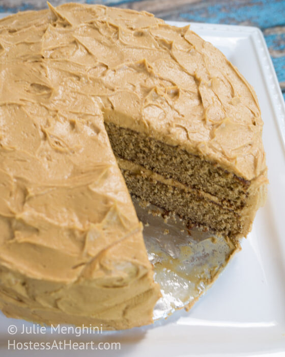 A round layered Spice Cake with Peanut Butter frosting on top and between the layers. The cake is sitting on a white cake stand.