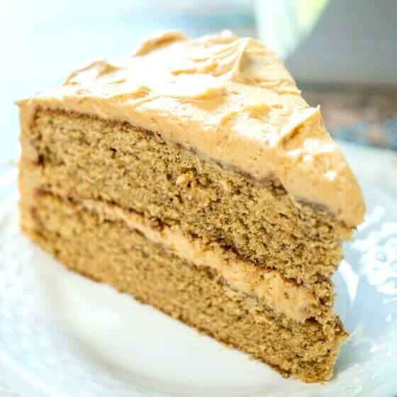 A slice of a layered peanut butter cake that\'s filled and frosted with peanut butter icing.
