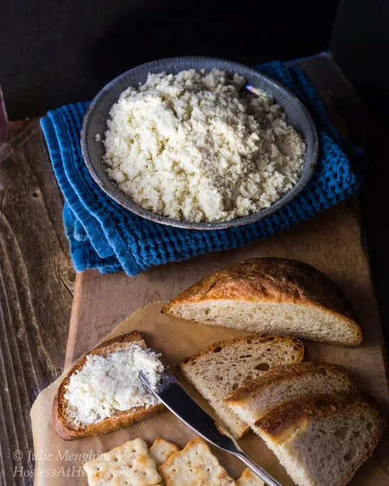 Blue bowl holding a cheese spread sitting next to serving crackers and sliced bread.