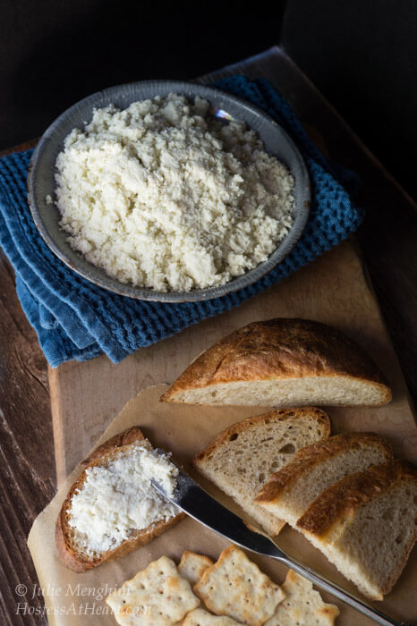 Blue bowl holding a cheese spread sitting next to serving crackers and sliced bread.