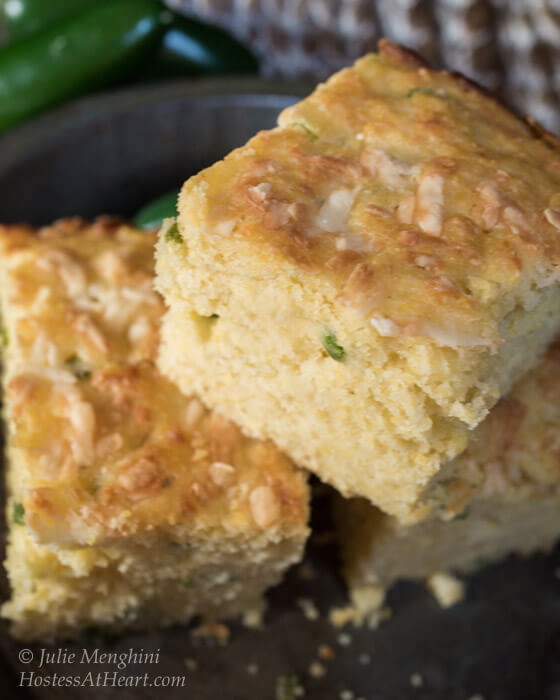 Three slices of Jalapeno Cheddar Cornbread surrounded by fresh jalapenos.