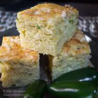 Three slices of Jalapeno Cheddar Cornbread surrounded by fresh jalapenos.