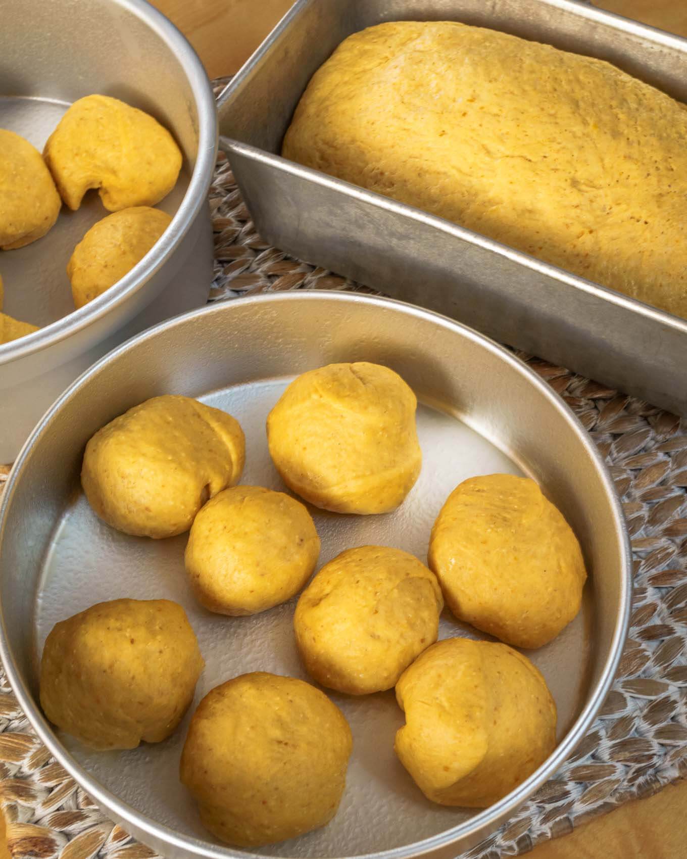 An unbaked loaf of Pumpkin Yeast Bread with individual rolls in the background.