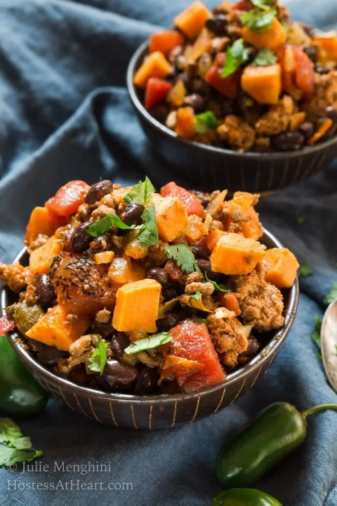 Two bowls of Sweet Potatoe and Black Been Chili sitting on a blue napkin.