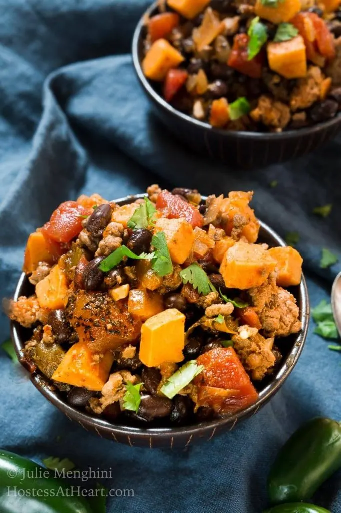 Two bowls of Sweet Potatoe and Black Been Chili sitting on a blue napkin.