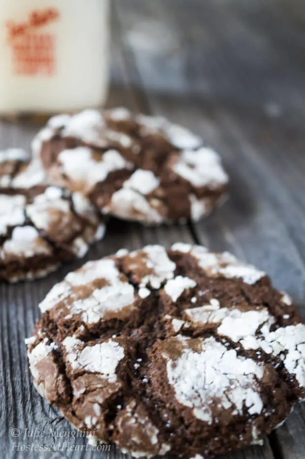 Chocolate crinkle cookies sitting on a wooden background.