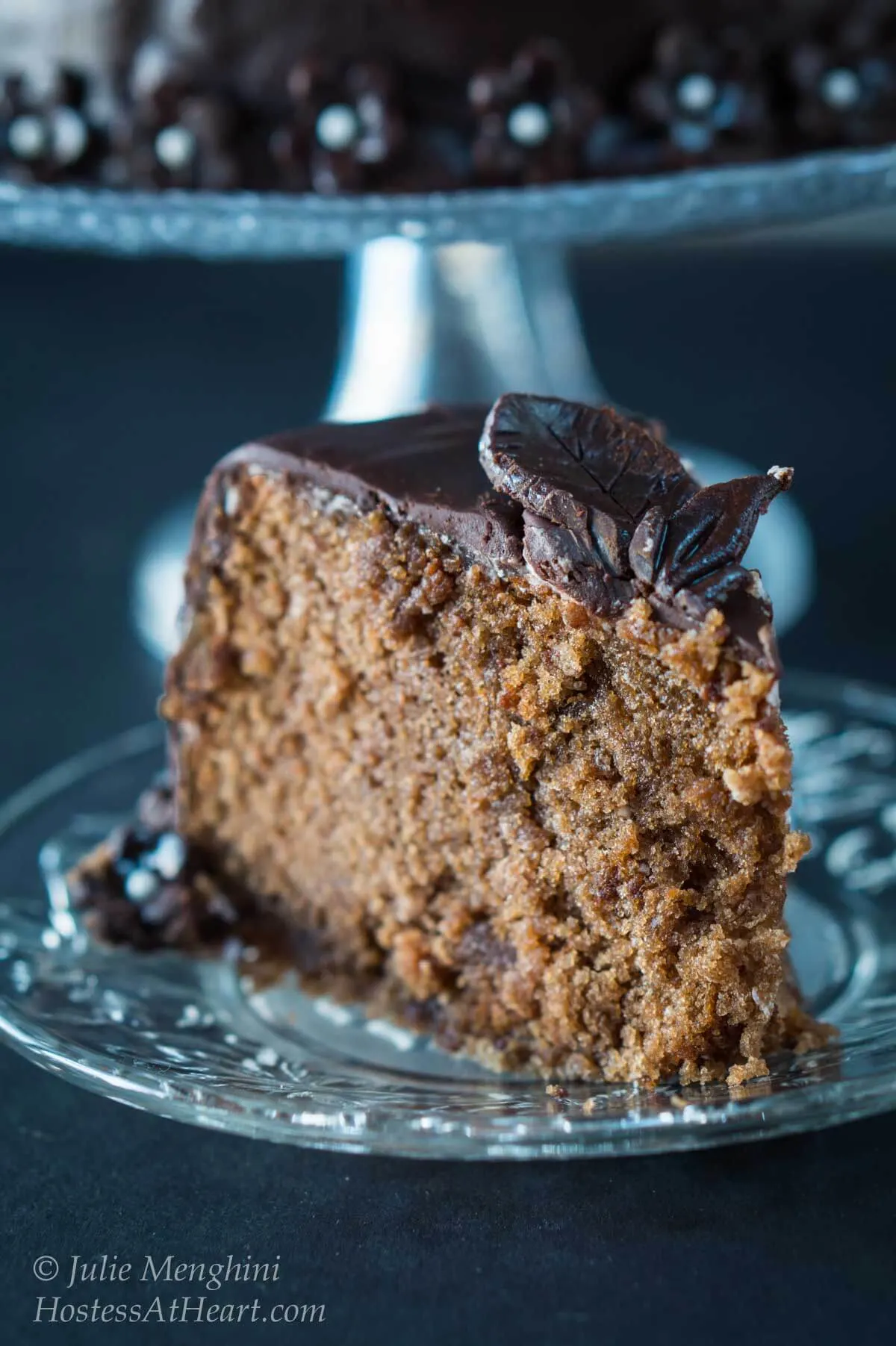 A piece of chocolate cake on a plate, topped with model chocolate flowers.