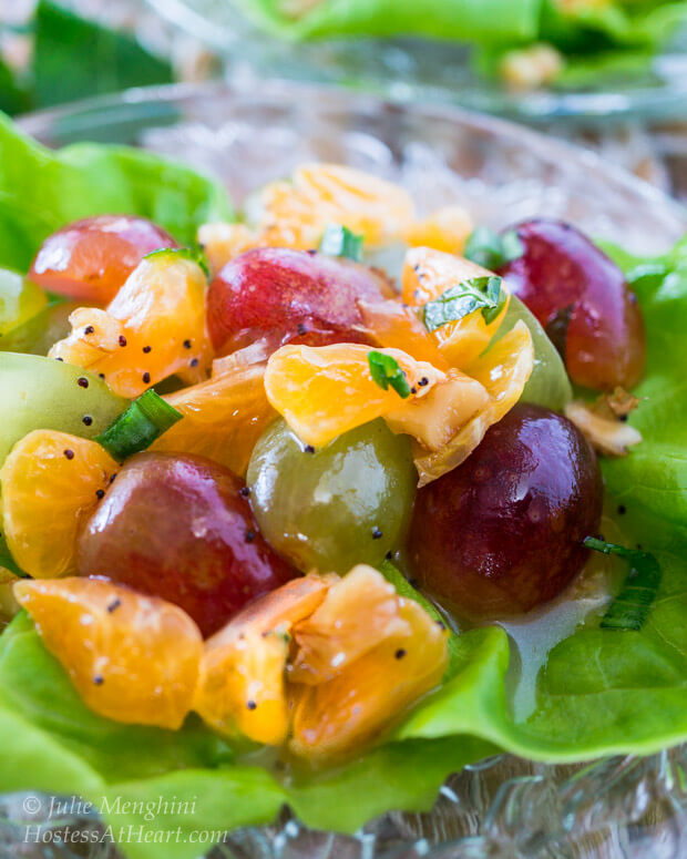 Butter lettuce leaf filled with a fruit salad made of grapes and clementines sitting on a glass plate.