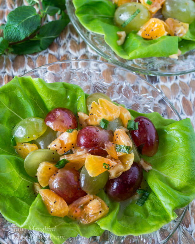 Butter lettuce leaf filled with a fruit salad made of grapes and clementines sitting on a glass plate.