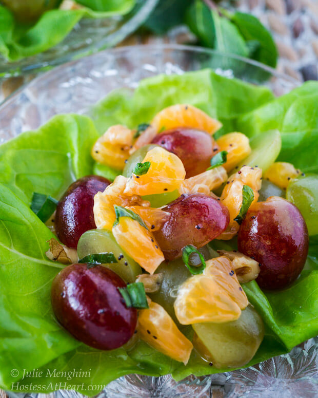 Butter lettuce leaf filled with a fruit salad made of grapes and clementines sitting on a glass plate.