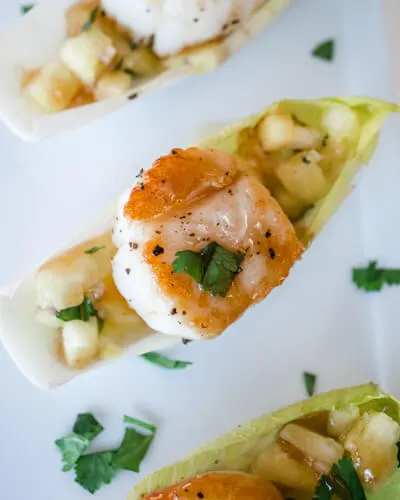 Scallops with Pineapple Salsa and Plum Wasabi Drizzle sitting in an endrive leaf