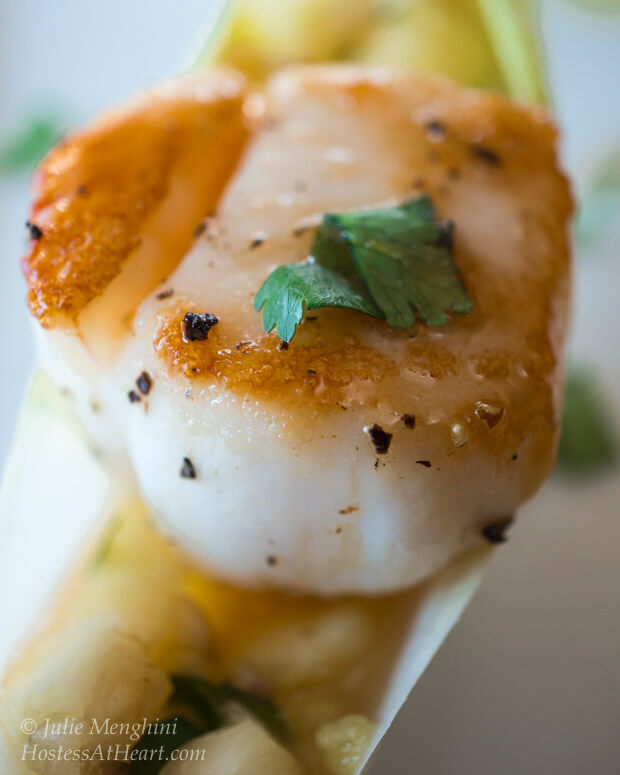 A close up a cooked scallop garnished with fresh parsley.