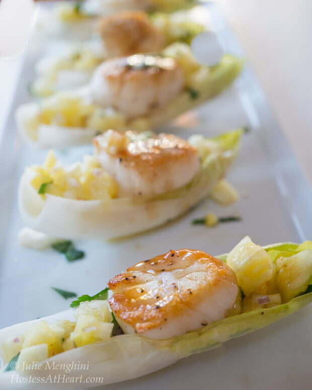 Cooked scallops on endive lettuce leaves topped with pineapple salsa.