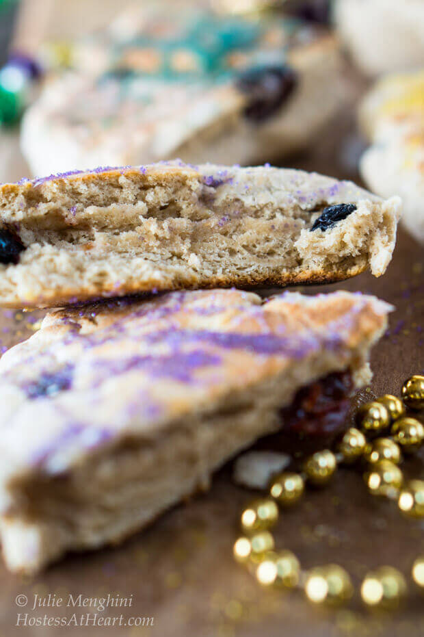 Slices of scones decorated with colored sugar with gold beads sitting in the front for Mardi Gras.