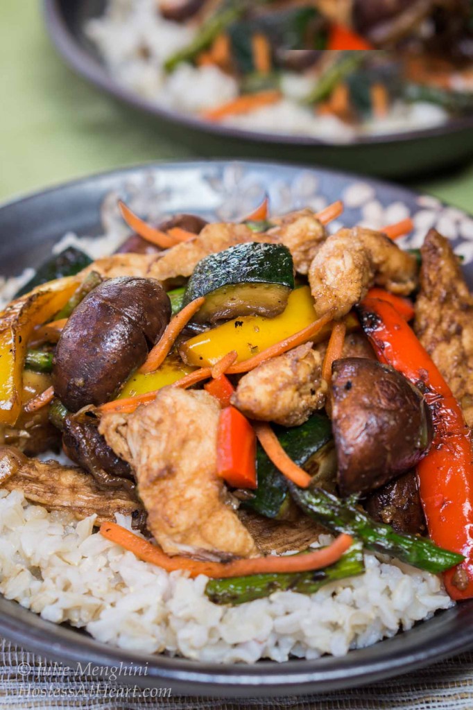 A bowl of white rice topped with chicken and vegetable stirfry.