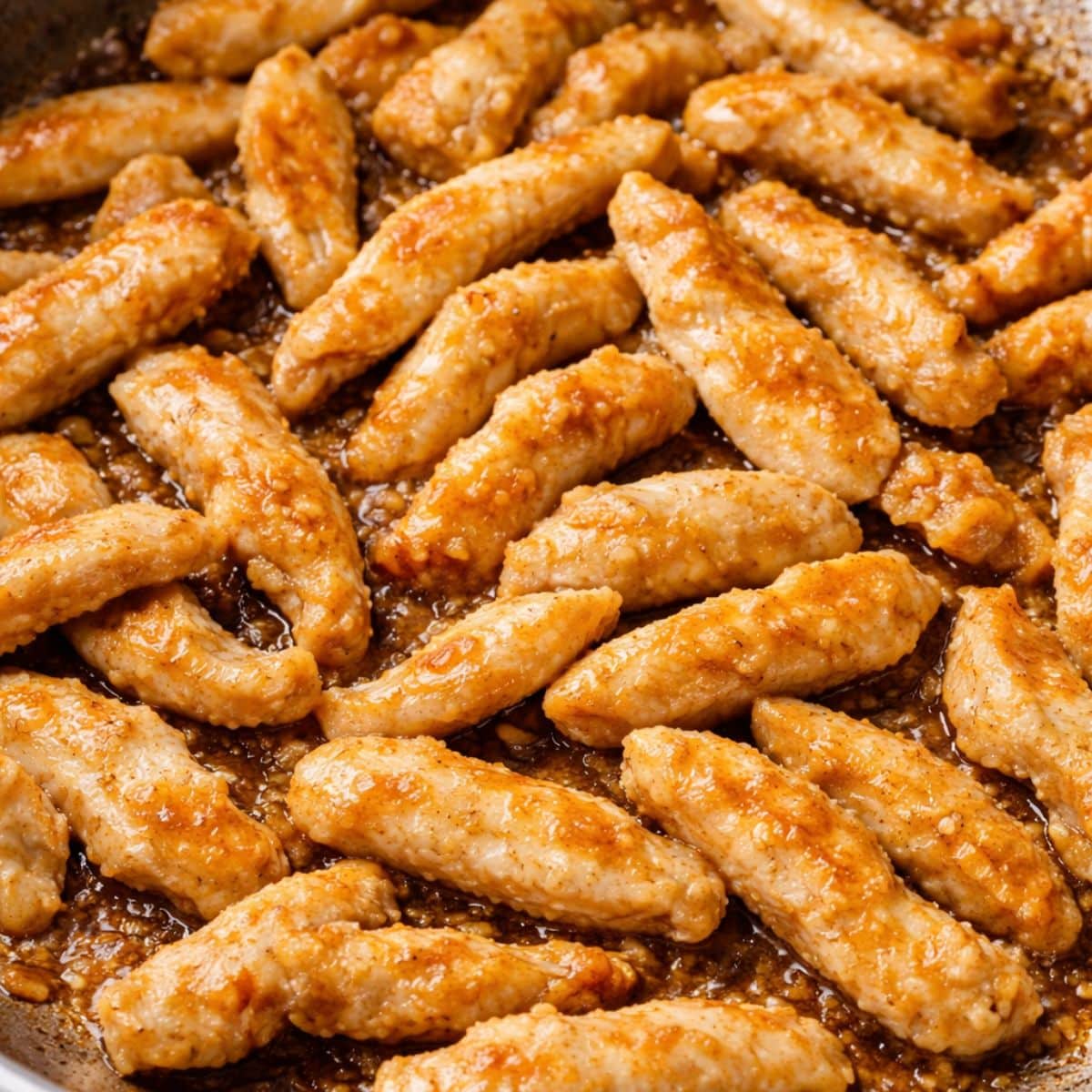 Lightly browned strips of chicken in a skillet. Hostess At Heart