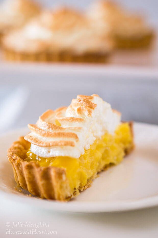 A pineapple meringue tart cut in half on a white plate.