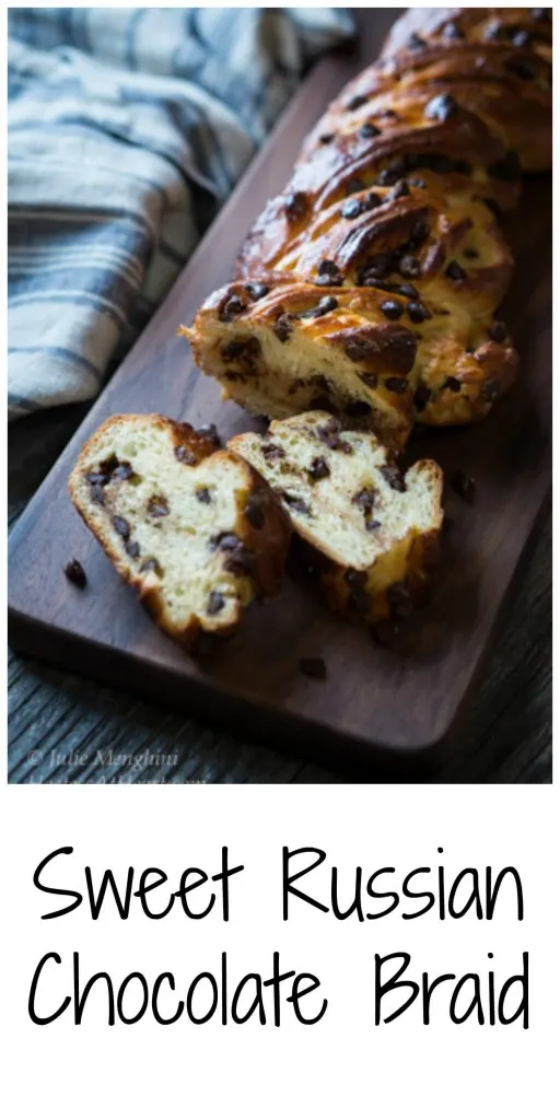 A braided chocolate bread on a bread wooden cutting board over a blue striped towel