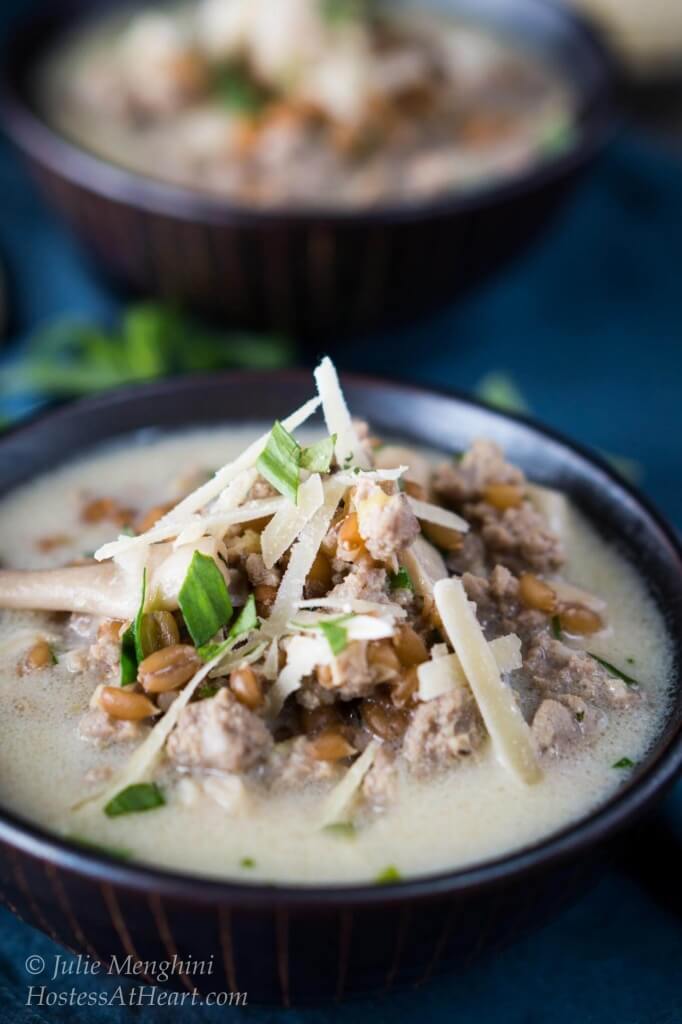 A bowl of ground turkey, mushrooms, and spelt, and garnished with parmesan cheese.