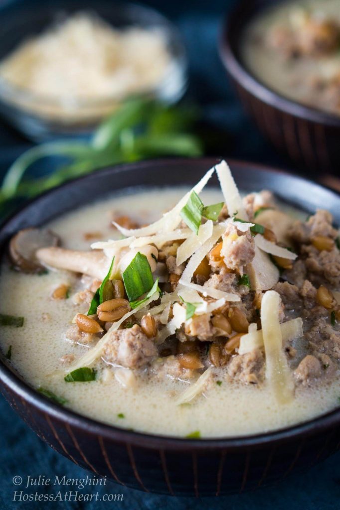 A bowl of ground turkey, mushrooms, and spelt, and garnished with parmesan cheese.