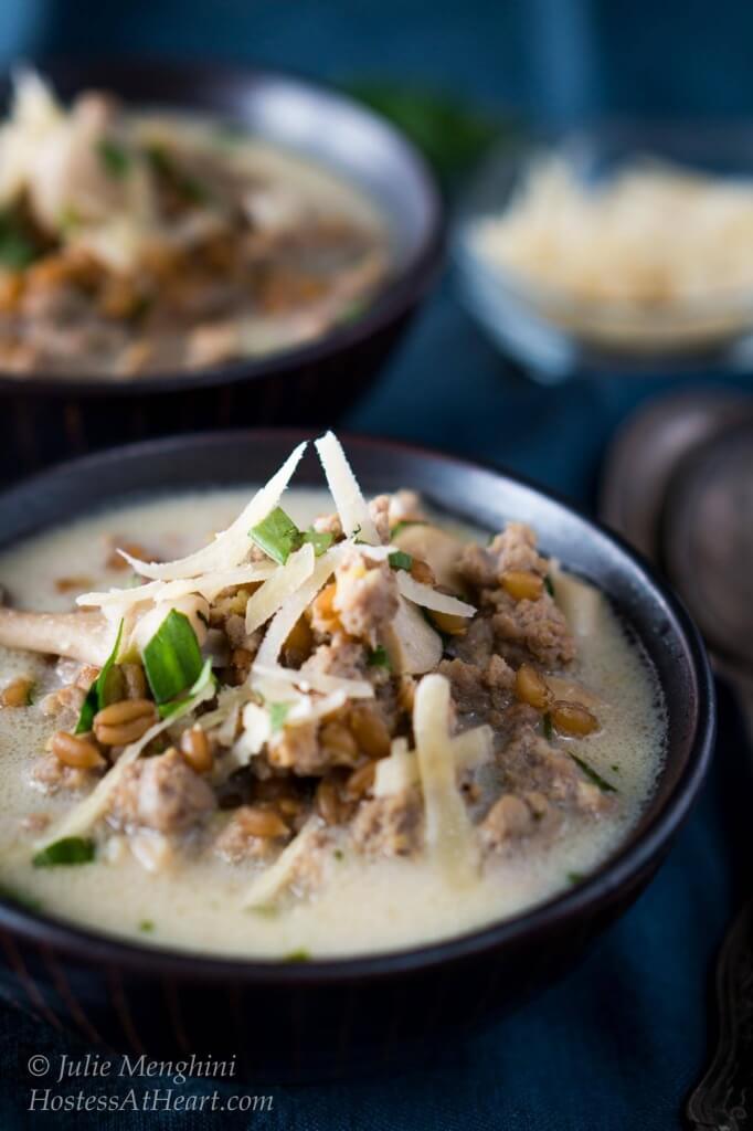 A bowl of ground turkey, mushrooms, and spelt, and garnished with parmesan cheese.