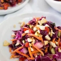 The beautiful colors in this Asian Cabbage Salad make for a show stopper dish. The crunchy veggies and cashew nuts are tossed in a ginger sesame vinaigrette for one delicious salad | HostessAtHeart.com