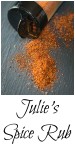 A spice jar laying on its side with the cap open and the spice rub spilling out on a piece of slate. The title "Julie's Spice Rub runs across the bottom.