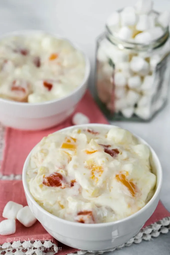 2 bowls of Tropical Fruit Cocktail Salad with a jar of marshmallows