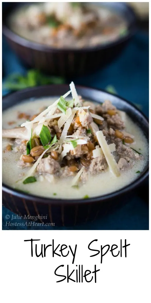 Angled photo of a black bowl filled with Ground Turkey and Spelt Skillet garnished with parmesan and parsley. A second bowl sits in the background.