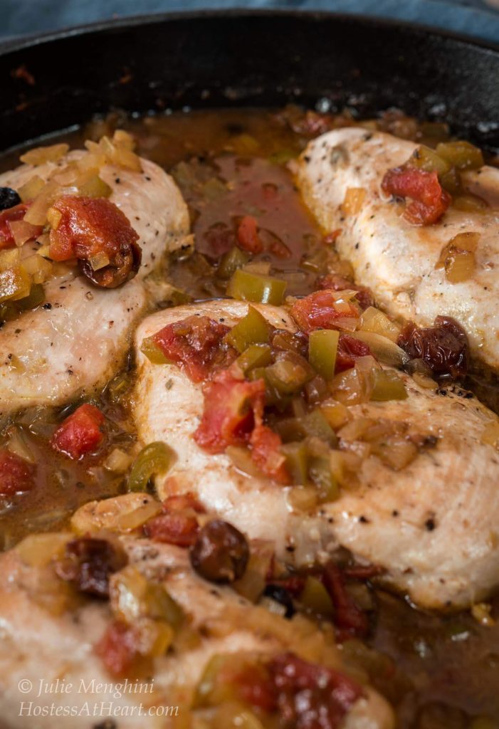 A skillet of Indian flavored Chicken breast topped with a sauce made with stewed tomatoes and green peppers.