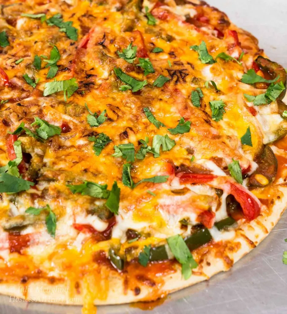 Top-down view of a of chicken fajita pizza that\'s been garnished with parsley.